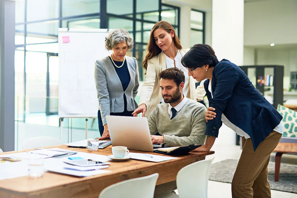 Technology professionals collaborating around a laptop in a modern office